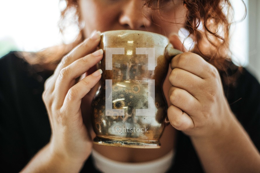 a woman sipping from a mug