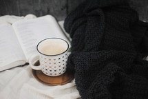 opened Bible, coffee cup, and blanket 