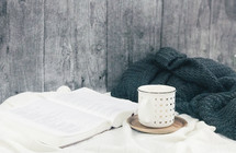 opened Bible, coffee cup, and blanket 