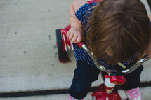 a toddler girl riding a red tricycle 