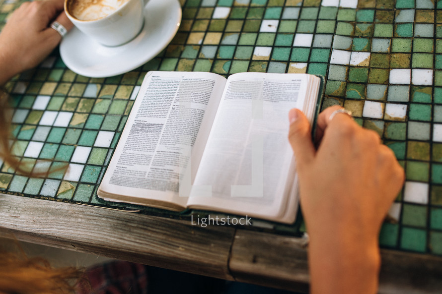 a woman reading a Bible at a coffee shop 