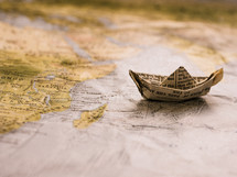 paper origami boat from the pages of a Bible on a world map 