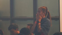 a woman covering her face with her hands during a worship service 