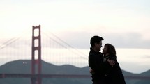 a cuddling couple by the Golden Gate bridge 