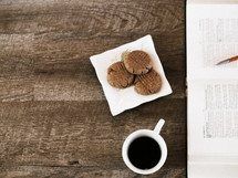 cookies on a napkin, coffee in a mug, and an open Bible 
