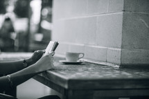 Hands holding a Bible on a table with a cup of coffee.