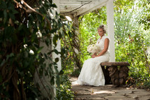 Bride sitting on a bench with flowers