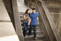 Couple in jeans holding hands while walking down cement steps.