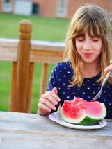 a girl child eating a watermelon 