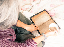 a woman reading a Bible on a bed and drinking coffee 