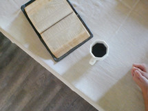open Bible and coffee mug on a tablecloth 
