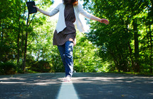 teen girl walking on the center lines of a road holding a Bible 