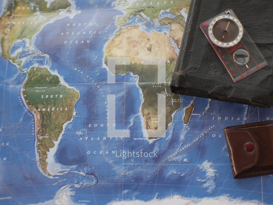 Bible, journal, compass, on a world map 