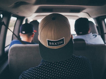 hats turned backwards on men riding in a van 