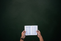 A woman's hands holding an open Bible.
