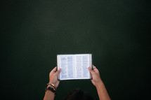 A woman's hands hold an open Bible.