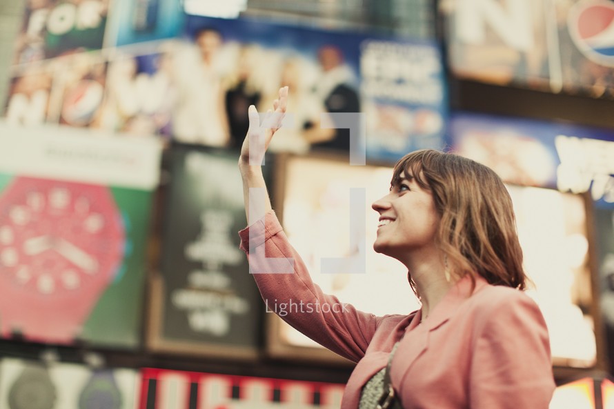 A young woman lifting her hand in Time Square 
