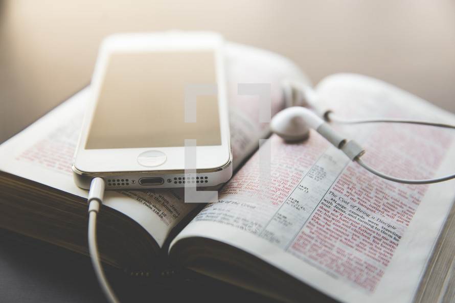 iPhone and earbuds on a Bible 