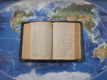 an open Bible on a world map 