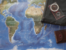 Bible, journal, compass, on a world map 