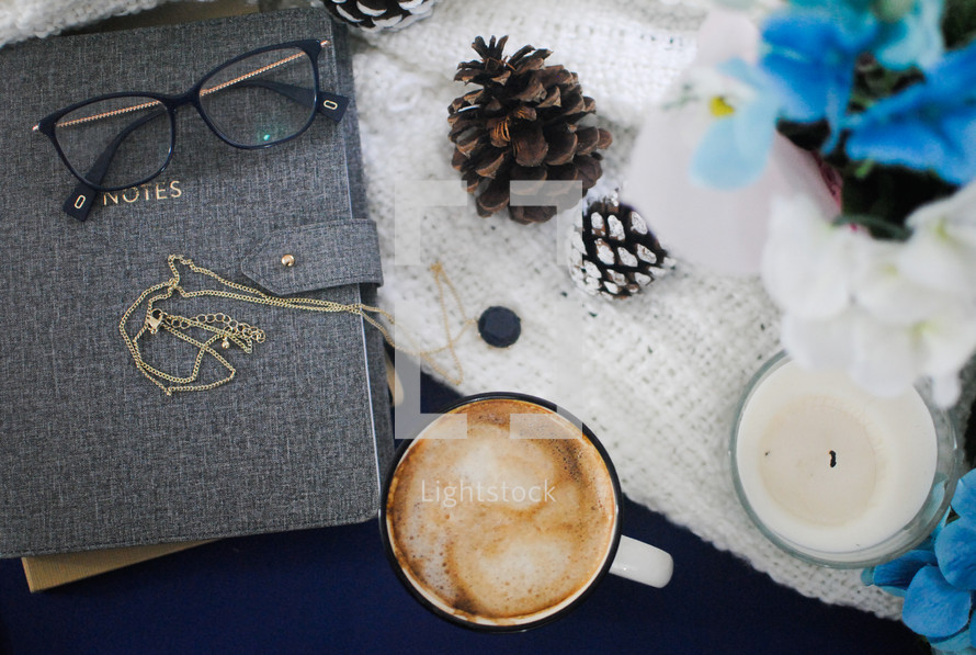 journal, reading glasses, coffee cup, and candle 