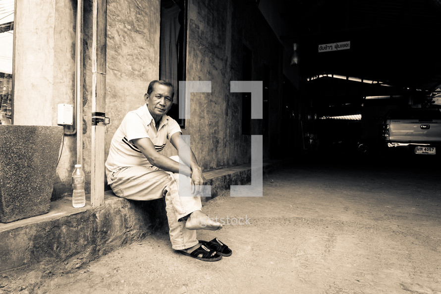 a man sitting on a curb resting his feet 