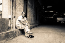 a man sitting on a curb resting his feet 