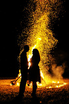 couple standing in front of a fire 