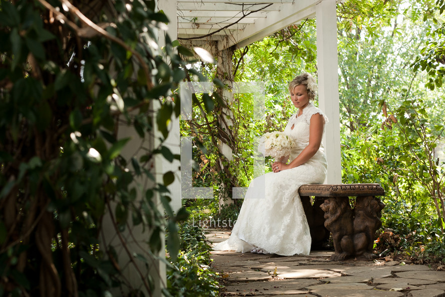 Bride sitting on a bench with flowers