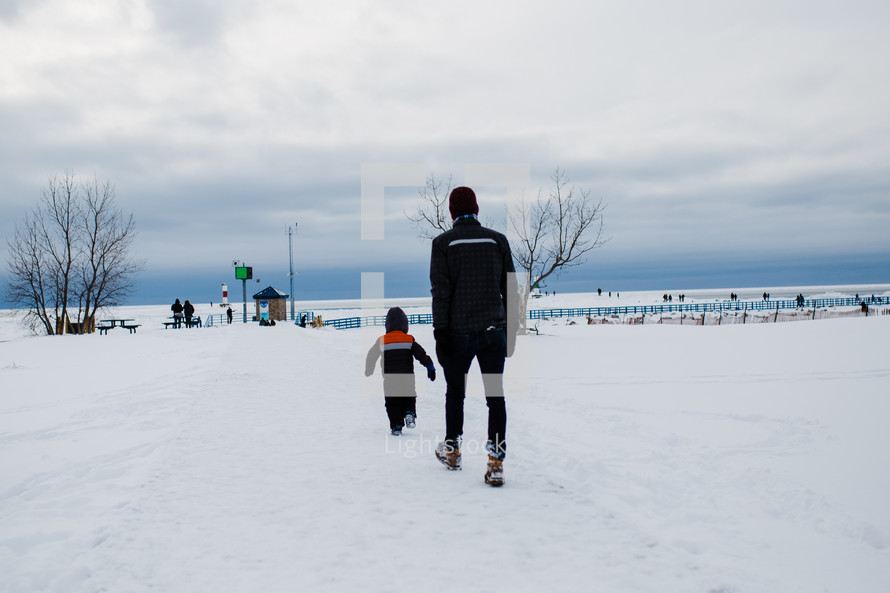 father and son walking through snow 