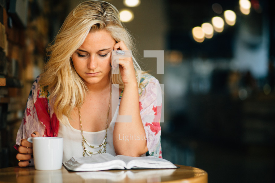 A young woman studying the Bible with a cup of coffee.