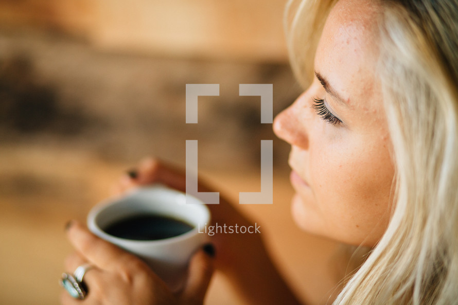 A thoughtful young woman holds a cup of coffee.
