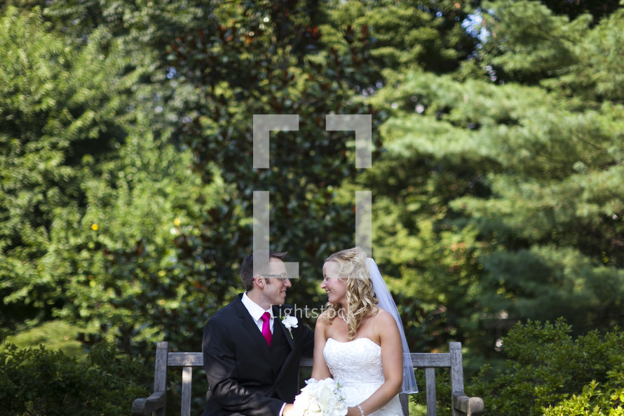 Happy bride and groom sitting on bench