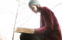 a woman reading a Bible outdoors in fall 