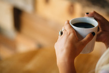 A cup of coffee held by a woman.