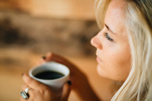 A thoughtful young woman holds a cup of coffee.