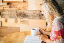 A young woman reads the Bible with a cup of coffee.