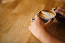 A cup of latte' held by a woman.