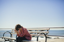 A young woman prays on a park bench