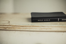 A Bible rests on a piece of white wood