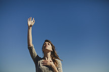woman with hand raised and hand over her heart