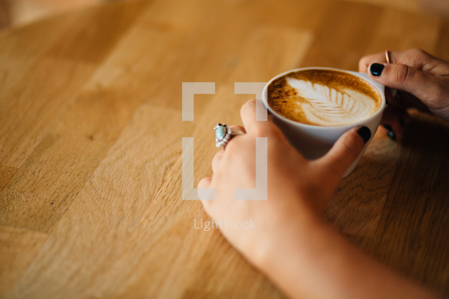 A cup of latte' held by a woman.