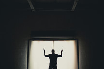 Silhouette of a man with hands raised in worship 