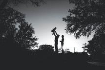 silhouette of a father holding his toddler daughter in the air