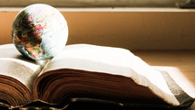 a globe on the pages of a Bible 