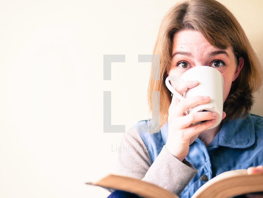 a woman reading the Bible and drinking coffee 