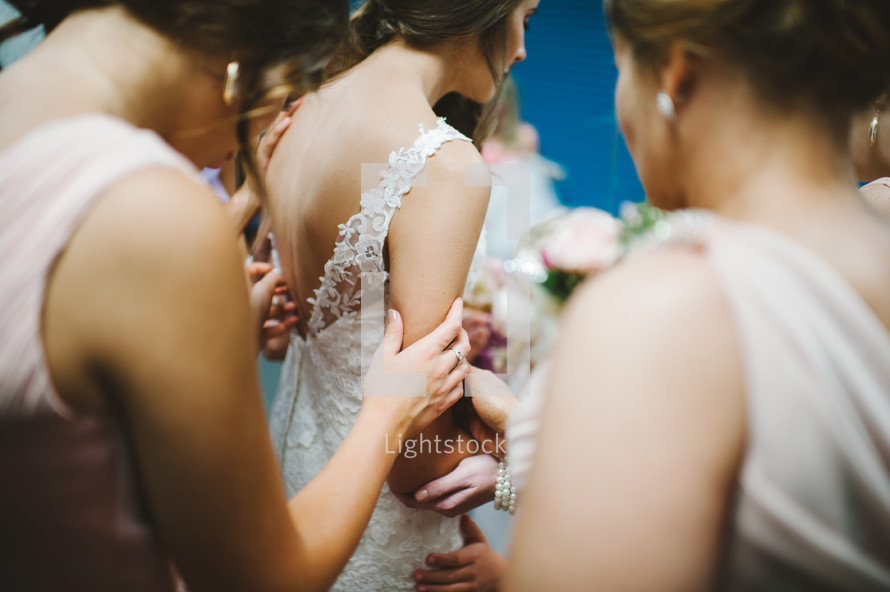 bridesmaids praying with the bride before the wedding 