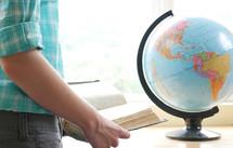 teen girl reading a Bible next to a globe 