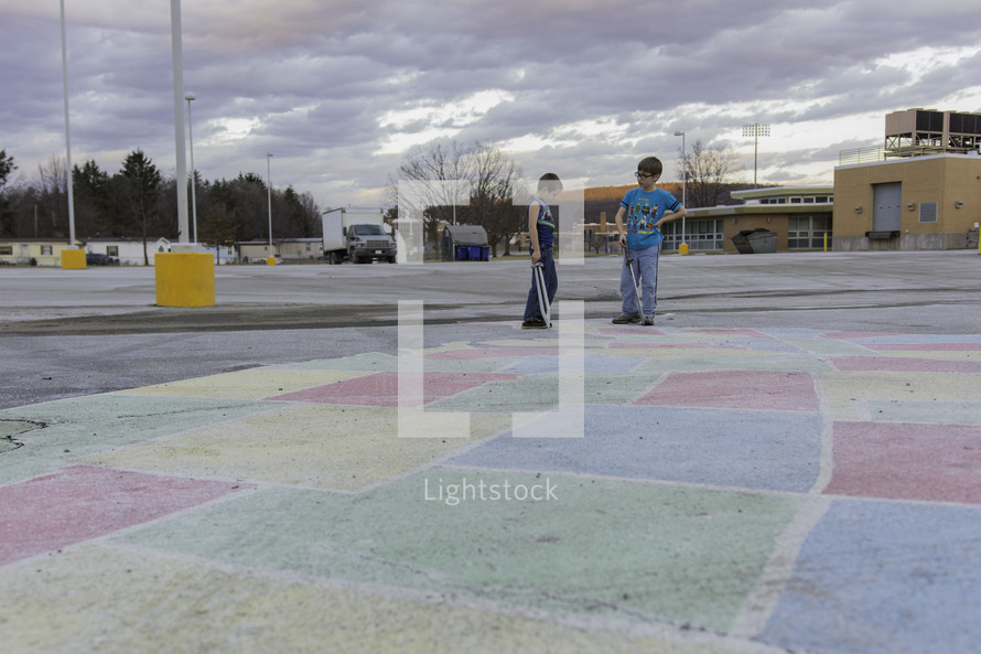 children coloring a parking lot with sidewalk chalk 