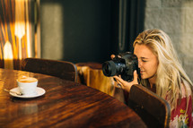 a woman taking a picture of a coffee cup 